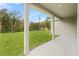 Covered back porch with a lovely view of a large grassy backyard and bordering trees at 16146 Sw 24Th Court Rd, Ocala, FL 34473