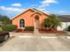 Charming single story home with an orange exterior, arched window, and mature landscaping at 1727 Winter Green Blvd, Winter Park, FL 32792