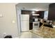 Kitchen with dark cabinets, white appliances, and granite countertops at 1948 Lake Atriums Cir # 113, Orlando, FL 32839