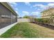 View of the backyard and screened patio, showcasing green grass and privacy fencing at 2797 Monticello Way, Kissimmee, FL 34741