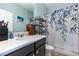 Bright bathroom featuring a vanity with a sink, storage shelves, and a shower with a decorative floral curtain at 2797 Monticello Way, Kissimmee, FL 34741