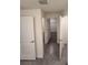 Hallway with gray tile flooring, white doors, and views into the bathroom and closet at 3223 Evenmore Way, Wildwood, FL 34785