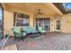 Comfortable covered patio featuring brick flooring, seating area, and ceiling fan at 323 Villa Sorrento Cir, Haines City, FL 33844