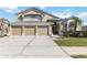 Two-story home with a tan exterior and a three-car garage with a well-maintained lawn and landscaping at 3262 Amaca Cir, Orlando, FL 32837