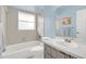 Bright blue bathroom featuring a vanity with a wooden cabinet and shower/tub with gray tiled walls at 328 Bridle Path, Casselberry, FL 32707