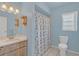 Bright blue bathroom featuring a vanity with a wooden cabinet and shower/tub with patterned curtain at 328 Bridle Path, Casselberry, FL 32707