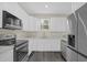 Bright kitchen with stainless steel appliances, white cabinets, and white countertops, complemented by dark wood-look flooring at 3778 Martin St, Orlando, FL 32806