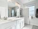 This is a bathroom with a double sink, a large mirror, and white cabinets at 431 Scotsmans Pl, Debary, FL 32713