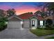 Charming single-story home with a brick driveway, stone accents, and a tile roof at sunset at 448 Douglas Edward Dr, Ocoee, FL 34761