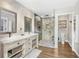 Bright bathroom featuring a double vanity, stone accent wall, and glass shower enclosure at 533 Balmoral Rd, Winter Park, FL 32789