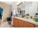 Bathroom with double sinks, wood cabinets, tile floor, and a mirror with accent lighting at 5361 Tortuga Dr, Orlando, FL 32837