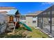 Backyard play area with a playset, adjacent to a screened-in lanai, creating a fun and safe space for children at 644 Strihal Loop, Oakland, FL 34787