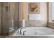 Close-up of a soaking tub with a tile surround, decorative accents, and a view of the glass-enclosed shower at 644 Strihal Loop, Oakland, FL 34787