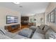 Open-concept living room features a large gray sectional, wooden floors and an open view of the kitchen at 644 Strihal Loop, Oakland, FL 34787