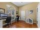 Bright home office featuring a large arched window, hardwood floors, and custom built-in cabinets at 644 Strihal Loop, Oakland, FL 34787