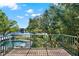 Balcony view featuring lush trees, a pool and lake under a sunny, partly cloudy sky at 7496 Lake Marsha Dr, Orlando, FL 32819