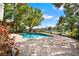 Landscaped pool area with lush greenery, brick pavers, and mature shade trees at 7496 Lake Marsha Dr, Orlando, FL 32819