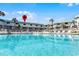 A lovely pool in front of the condo complex, surrounded by chairs and palm trees under a sunny sky at 815 Ocean Shore Blvd # U7A, Ormond Beach, FL 32176