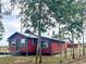 Side view of a red home featuring a modern porch, set within a wooded landscape at 111 Water Tank Rd, Haines City, FL 33844