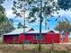 Rear view of a red house with a silver roof, fenced yard and HVAC unit at 111 Water Tank Rd, Haines City, FL 33844