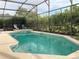 Sparkling private pool with tiled edges surrounded by lush landscaping and screened enclosure at 114 Langham Dr, Davenport, FL 33897