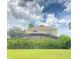 Backyard view of the screened-in pool area, featuring a spacious grassy area, and surrounded by greenery at 114 Langham Dr, Davenport, FL 33897