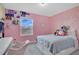 Bright bedroom with pink walls, gold polka dots, a full-sized bed, and a desk under the window at 11867 Pulitzer Pl, Orlando, FL 32832