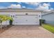 Garage exterior showcasing a two-car garage, paver driveway, fresh landscaping, and well-maintained lawn at 11867 Pulitzer Pl, Orlando, FL 32832