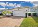 Exterior view of a two-car garage with a brick paver driveway and well-maintained landscaping at 11867 Pulitzer Pl, Orlando, FL 32832