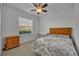 This bedroom has a ceiling fan and a window with wooden furniture and patterned bedding at 15506 Gemini Dr, Mascotte, FL 34753