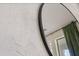 Close-up of a round mirror and textured wall in a bedroom, with a glimpse of a window at 18339 Oliver Twist Way, Winter Garden, FL 34787