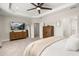 Spacious primary bedroom featuring a tray ceiling, wood furniture, and a mounted TV at 18339 Oliver Twist Way, Winter Garden, FL 34787