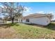 Grassy backyard with a concrete patio, white house, and a clear blue sky at 1909 Michigan Way, Poinciana, FL 34759