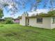 View of the back of the house with a spacious lawn, a chimney, and some mature trees at 23 Judith Ln, Orlando, FL 32811