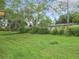 A large grassy backyard featuring a few large trees, an adjacent house with a large overgrown area at 23 Judith Ln, Orlando, FL 32811