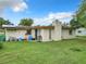 A house with solar panels, a small backyard patio, and minimal landscaping on a green lawn at 23 Judith Ln, Orlando, FL 32811