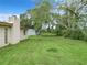 A wide, grassy backyard with trees and a fence, attached to a single-story home with a brick chimney at 23 Judith Ln, Orlando, FL 32811