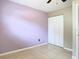 Bedroom with tile floors, a double closet and light purple accent wall at 23 Judith Ln, Orlando, FL 32811