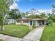 A single-story home with a well-maintained lawn, solar panels, and a walkway that leads to a vibrant blue front door at 23 Judith Ln, Orlando, FL 32811