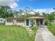 A single-story home with a well-maintained lawn, solar panels, and a walkway that leads to a vibrant blue front door at 23 Judith Ln, Orlando, FL 32811