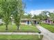 A single-story home with a well-maintained lawn, solar panels, and a walkway that leads to a vibrant blue front door at 23 Judith Ln, Orlando, FL 32811