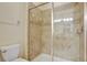 Well-lit shower with glass door and tiled walls with decorative accents, plus a toilet at 2383 Victoria Dr, Davenport, FL 33837