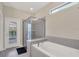 Bathroom with a soaking tub, glass-enclosed shower, and natural light from a transom window at 2483 Dubai St, Kissimmee, FL 34747