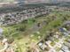 An aerial view of a residential area adjacent to a lush green golf course with mature trees and a pond at 2625 Albion Ave, Orlando, FL 32833