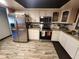 White cabinets with a stainless steel refrigerator and wood-look tile flooring at 3430 Kathy Ct, Lakeland, FL 33810