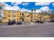 Low-angle view of a yellow two-story apartment building with ample parking and palm trees in the landscaping at 4536 Commander Dr # 1537, Orlando, FL 32822