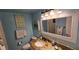 A well-lit bathroom with a granite countertop, decorated mirror, and a beach theme throughout at 4831 Saxon Dr # 1130, New Smyrna Beach, FL 32169