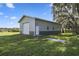 Exterior view of the barn featuring a large roll-up door, a single entry door, and exterior lighting at 5335 Canoe Creek Rd, St Cloud, FL 34772