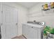 Bright laundry room with a white washer and dryer, shelving and tiled flooring at 545 Jerry Ln, Haines City, FL 33844