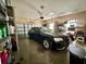 View of a clean garage with a parked black sedan, shelving and garage door at 546 Nogales Ct, Kissimmee, FL 34758